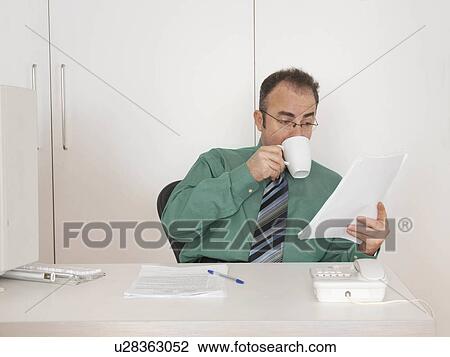 Businessman looking at papers View Large Photo Image Stock Image - Businessman looking at papers. Fotosearch