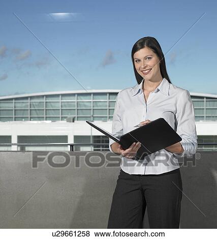 Businesswoman smiling, holding book View Large Photo Image Stock Photo - Businesswoman smiling, holding book. Fotosearch