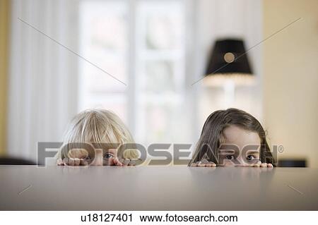 Stock Image - children looking over table edge. Fotosearch