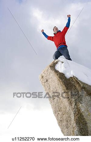 Stock Image - climber celebrating on snow capped peak. Fotosearch