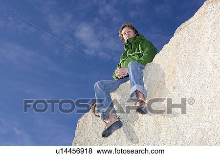 Stock Photo - Climber sitting on mountain peak. Fotosearch