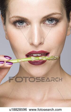 Stock Photograph - close up of female asparagus in mouth. Fotosearch