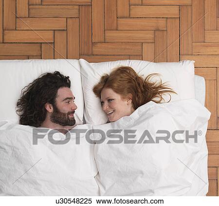 Couple lying in bed, smiling View Large Photo Image Stock Photography - Couple lying in bed, smiling. Fotosearch