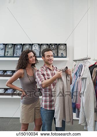 couple shopping holding up jacket View Large Photo Image Picture - couple shopping holding up jacket. Fotosearch