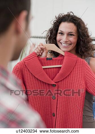 couple shopping holding up pullover View Large Photo Image Picture - couple shopping holding up pullover. Fotosearch