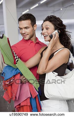Stock Photo - couple shopping looking at dresses. Fotosearch