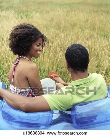 Picture - Couple sitting on blow up sofa outside. Fotosearch