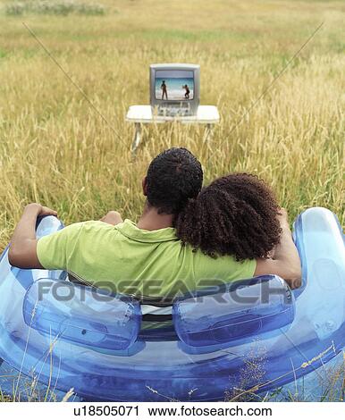 Couple sitting outside watching TV View Large Photo Image Stock Image - Couple sitting outside watching TV. Fotosearch