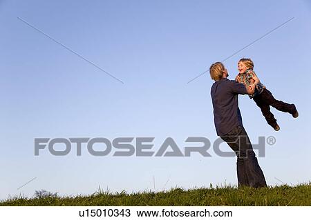 Stock Image - father spinning boy in his arms. Fotosearch