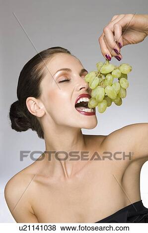 Stock Photo - female beauty eating grapes. Fotosearch