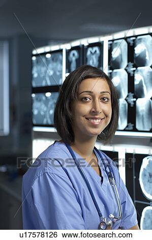 Stock Photograph - Female doctor, smiling, x-rays behind. Fotosearch