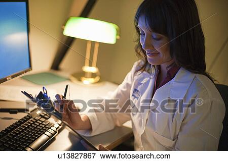 Female Doctor working at desk at night View Large Photo Image Stock Photo - Female Doctor working at desk at night. Fotosearch