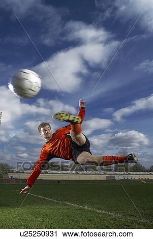Stock Image - footballer volleying ball mid air. Fotosearch