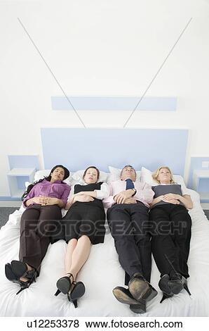 Four business people lying in a bed View Large Photo Image Stock Photo - Four business people lying in a bed. Fotosearch