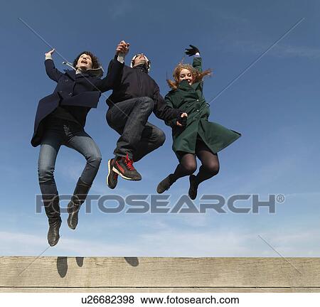 Friends leaping across wooden obstacle View Large Photo Image Stock Photo - Friends leaping across wooden obstacle. Fotosearch