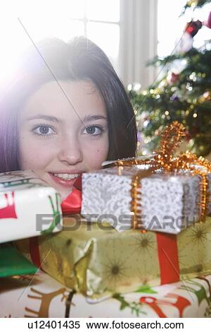 Stock Photography - Girl, 14 behind pile of presents. Fotosearch