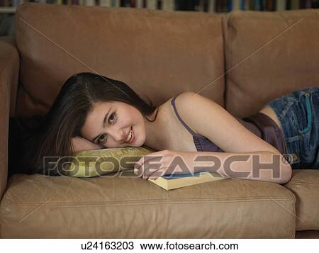 Stock Image - Girl, 14 smiling laying on sofa. Fotosearch