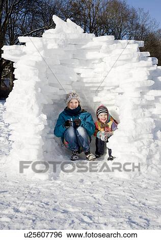 Stock Photograph - Girl and boy in igloo in the snow. Fotosearch