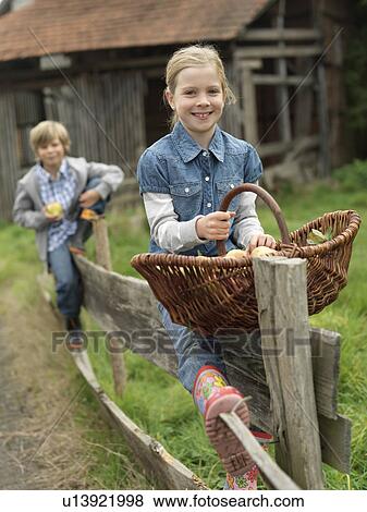 Girl and boy on fence with apples View Large Photo Image Stock Photo - Girl and boy on fence with apples. Fotosearch