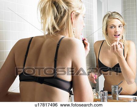 Stock Photograph - Girl applying makeup in bathroom. Fotosearch