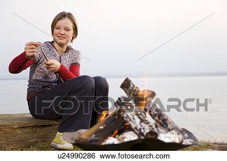 Stock Photograph - girl carving stick at barbecue fire. Fotosearch
