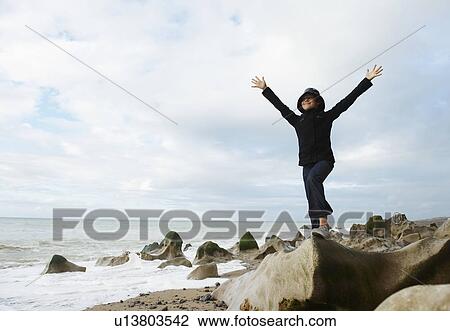 Stock Image - Girl spreading arms towards ocean. Fotosearch