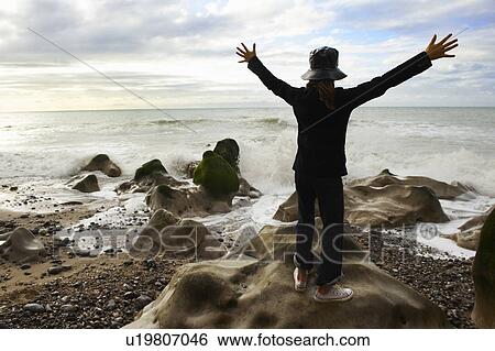 Stock Photograph - Girl spreading arms towards ocean. Fotosearch