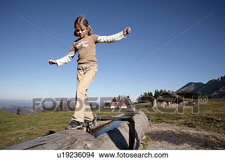 Picture - Girl walking along a log in mountains. Fotosearch