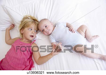 Stock Image - Girl with her baby brother, in bed. Fotosearch