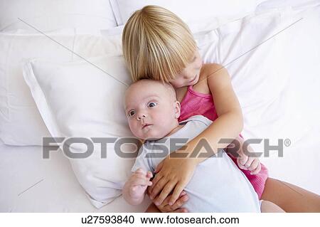 Stock Image - Girl with her baby brother, in bed. Fotosearch