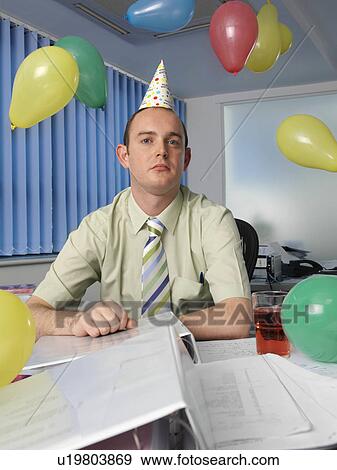 Grumpy office worker in party hat View Large Photo Image Stock Photo - Grumpy office worker in party hat. Fotosearch