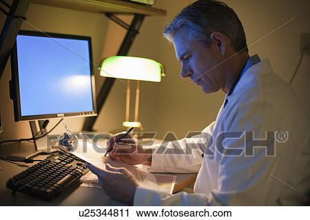 Male Doctor working at desk at night View Large Photo Image Stock Image - Male Doctor working at desk at night. Fotosearch