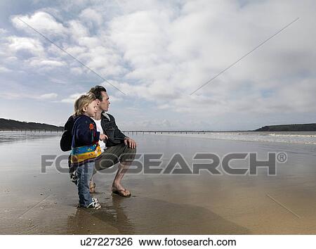 man and child looking out to sea on beach View Large Photo Image Stock Photograph - man and child looking out to sea on beach. Fotosearch
