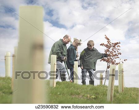 Stock Image - Man And Children Planting Trees. Fotosearch