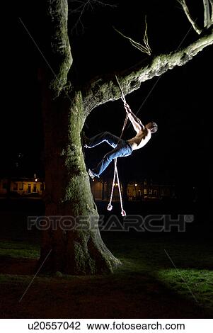 Stock Image - man climbing tree. Fotosearch