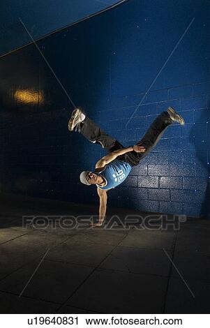 Stock Image - man doing one hand stand. Fotosearch