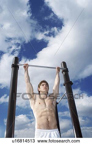 Stock Image - man hanging on pull up bar. Fotosearch