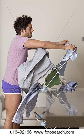Stock Photograph - man hanging up wet clothes on dryer. Fotosearch