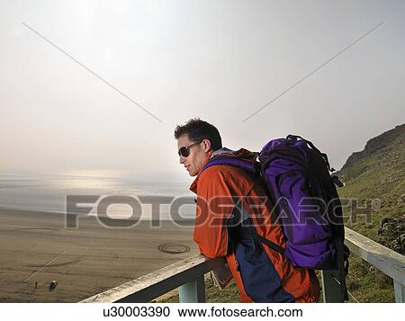 man hiking on cliff edge View Large Photo Image Stock Image - man hiking on cliff edge. Fotosearch
