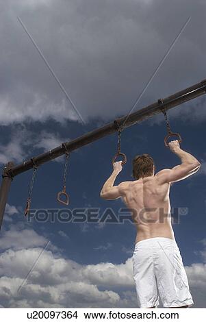 Picture - man holding pull up rings. Fotosearch