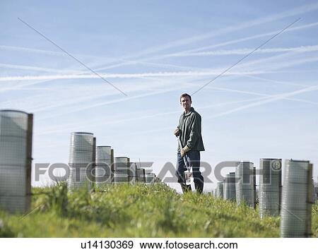 Stock Photo - Man In Field With Young Trees. Fotosearch