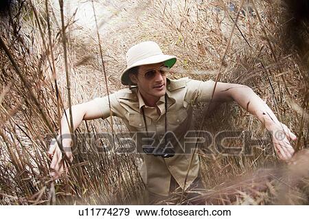 Stock Photo - man in jungle outfit wading riverside. Fotosearch