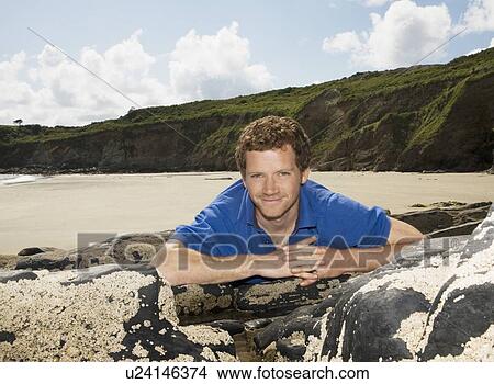 Picture - Man Leaning on Beach Rocks. Fotosearch