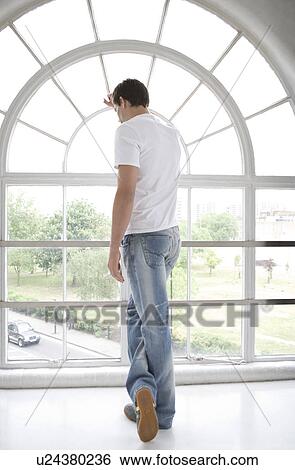 Stock Photograph - Man looking through a window.. Fotosearch