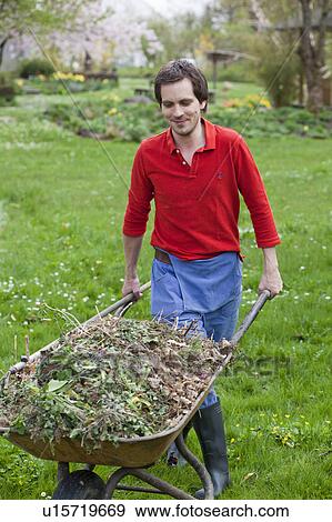 Stock Photo - man pushing wheelbarrow. Fotosearch