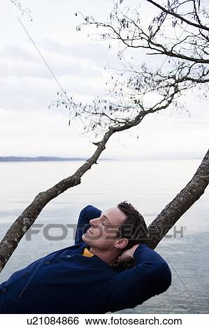 man resting on tree branch at lake View Large Photo Image Stock Photograph - man resting on tree branch at lake. Fotosearch