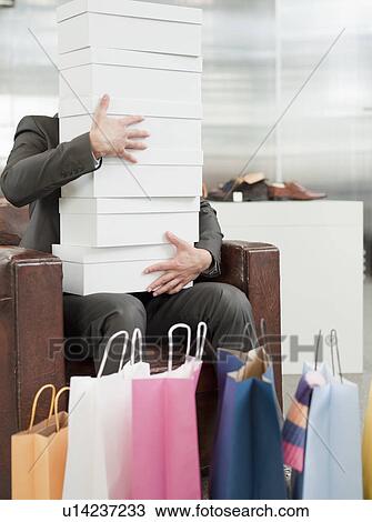 Stock Image - man shopping holding pile of cartons. Fotosearch
