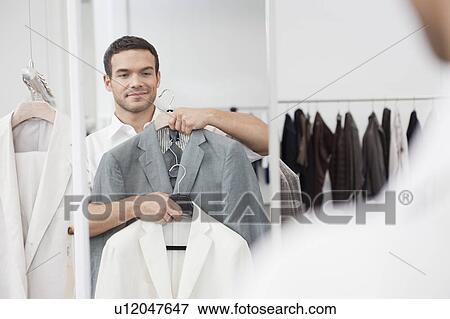 man shopping holding up jacket View Large Photo Image Stock Photo - man shopping holding up jacket. Fotosearch
