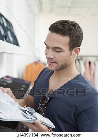 man shopping holding up shirt View Large Photo Image Picture - man shopping holding up shirt. Fotosearch
