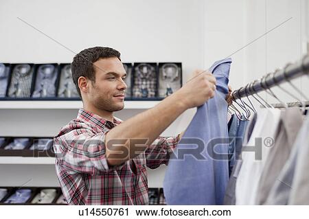 man shopping holding up shirt View Large Photo Image Stock Image - man shopping holding up shirt. Fotosearch